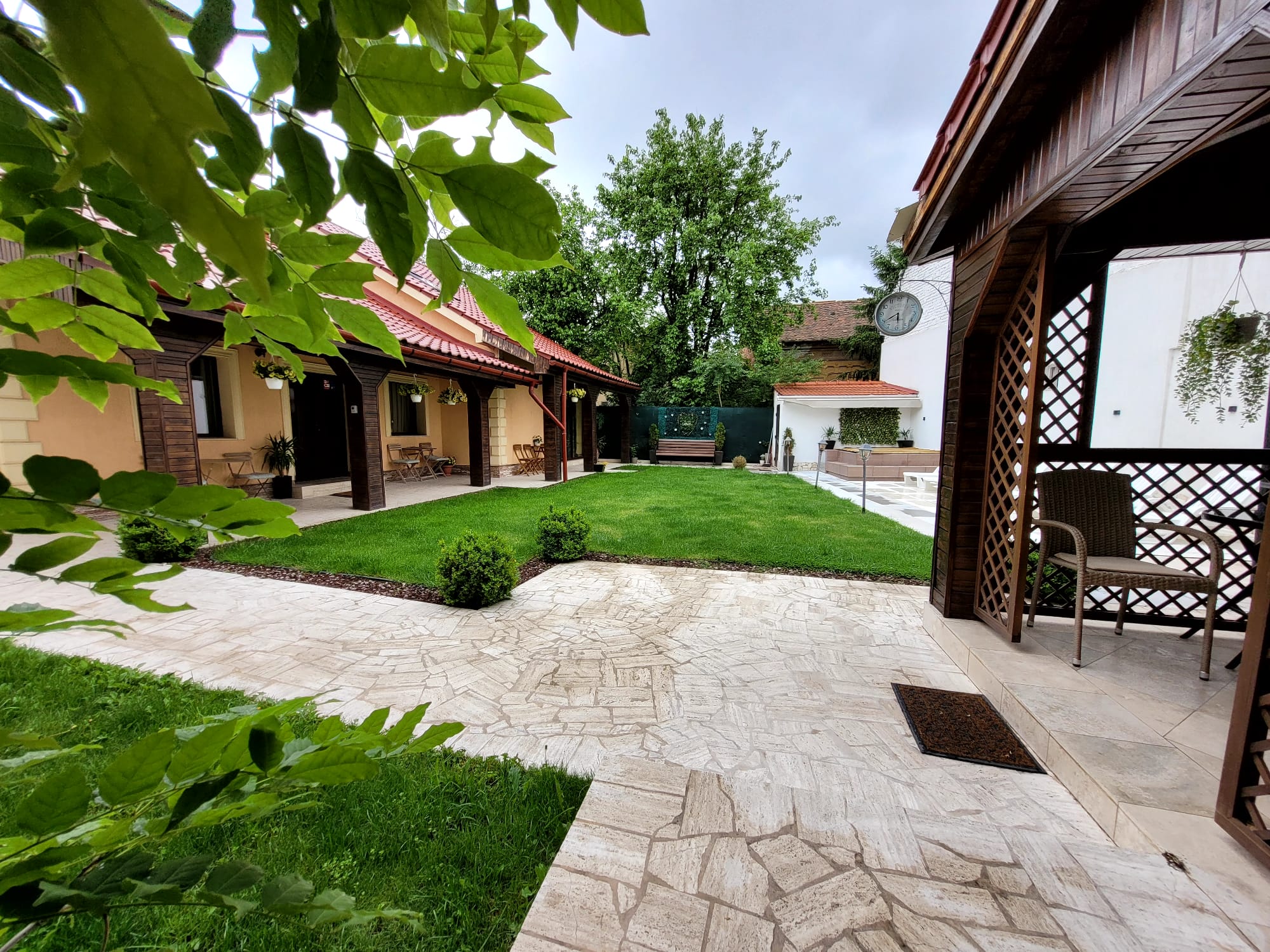 Curtea interioară Villa DeaDorata ziua — gazon, terasă travertin și foișor