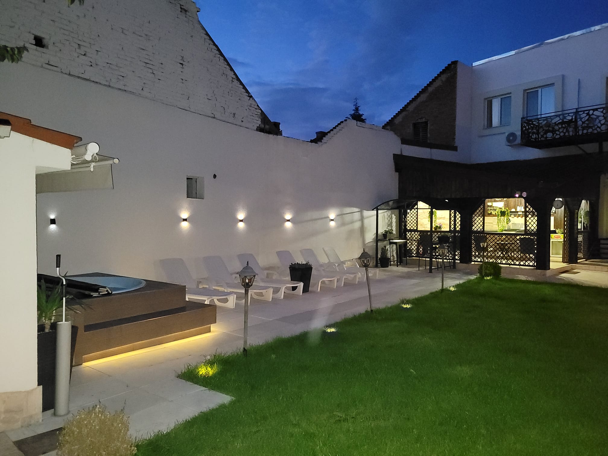 Zona jacuzzi și șezlonguri iluminate noaptea la Villa DeaDorata